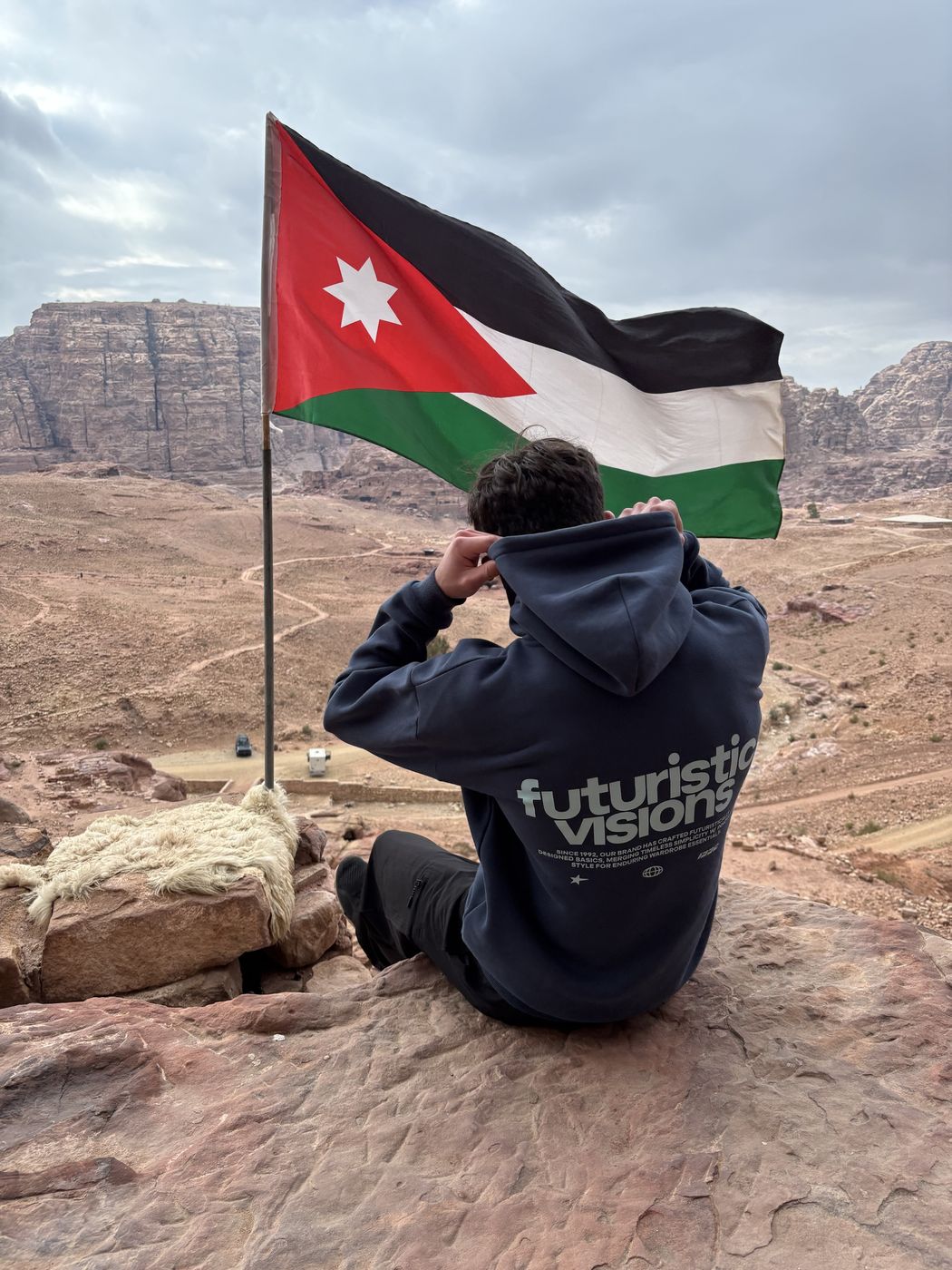 Jason sitting by the Jordanian flag above Petra